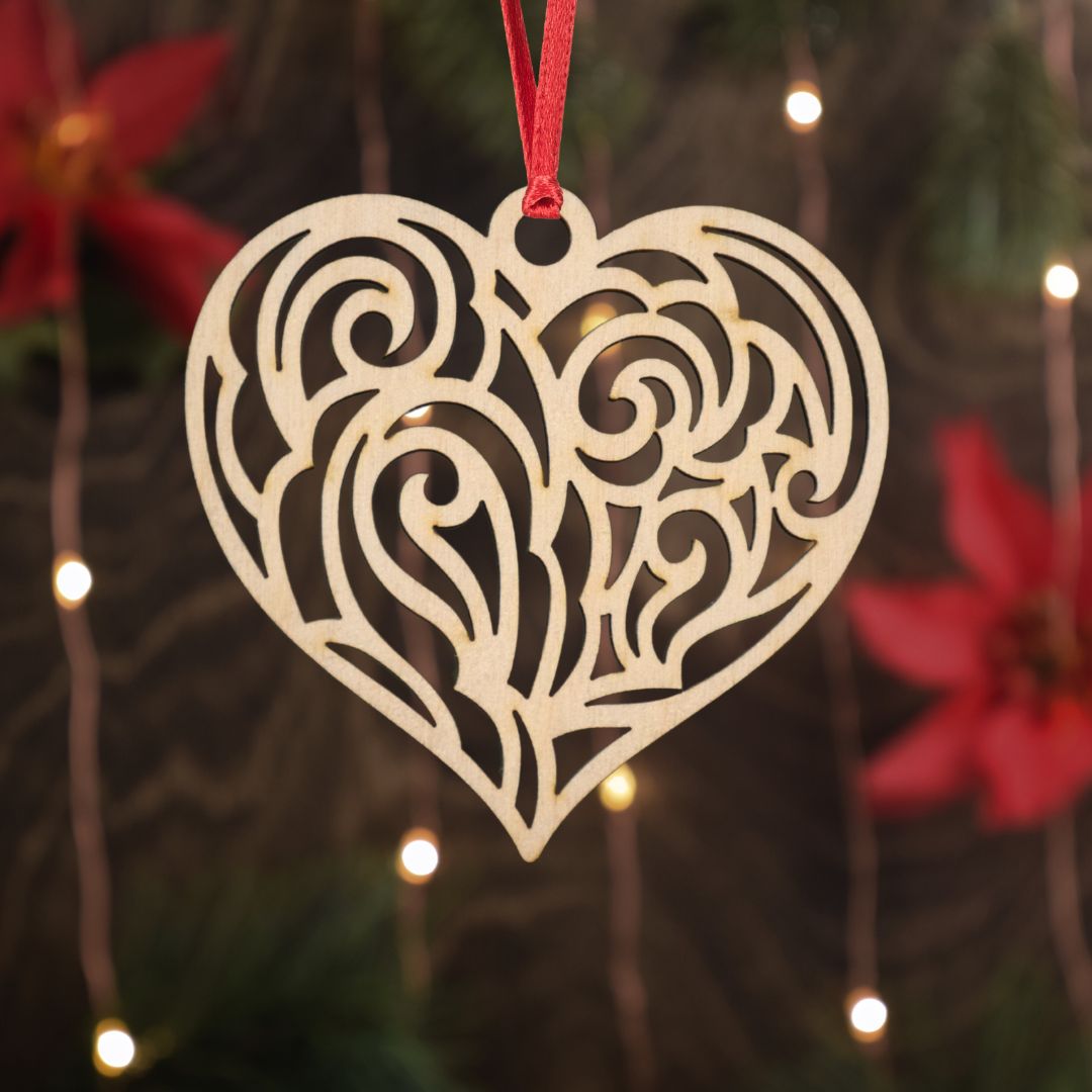 Decorative heart-shaped ornament with intricate patterns hanging against a blurred festive background.
