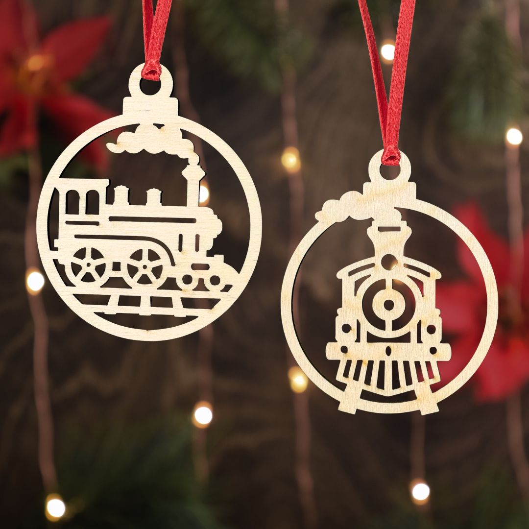 Two train-shaped Christmas ornaments hanging against a festive background with lights and red ribbons.