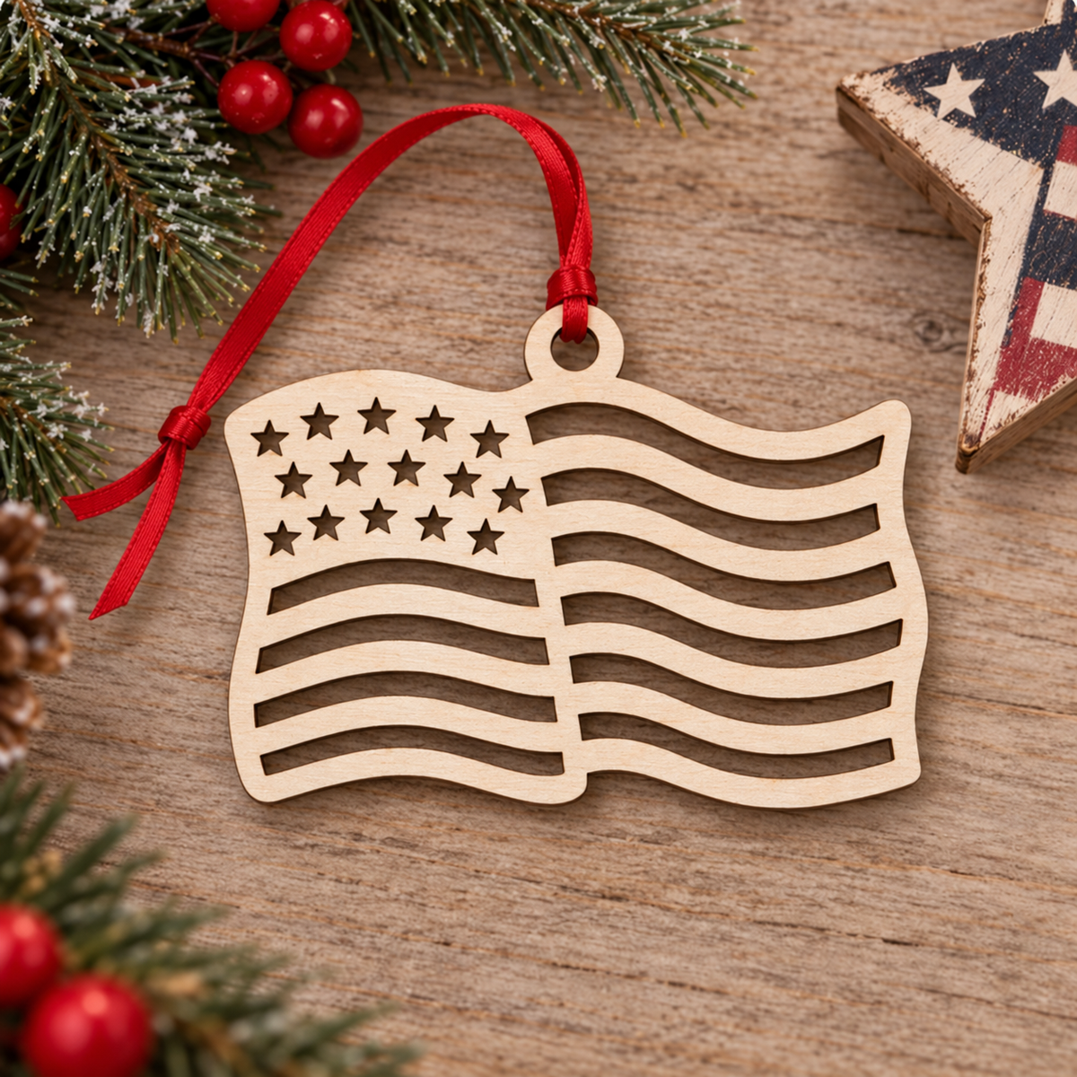 A wooden American flag ornament with a red ribbon hanger, displayed on a rustic wooden surface with holiday greenery and red berries.